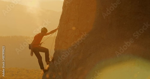 Climber climbing up the rock in amazing evening light.

