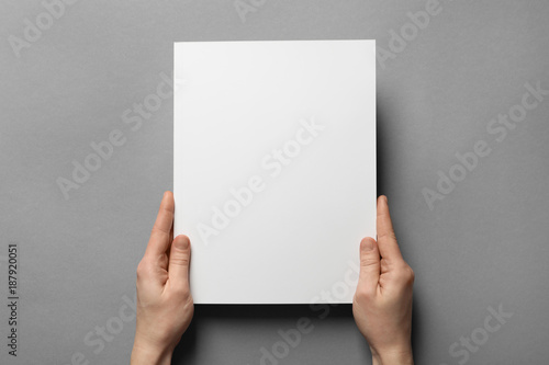 Woman holding brochure with blank cover on grey background. Mock up for design