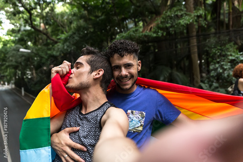 Canvas Print Gay Couple Taking a Selfie with Rainbow Flag in the Park
