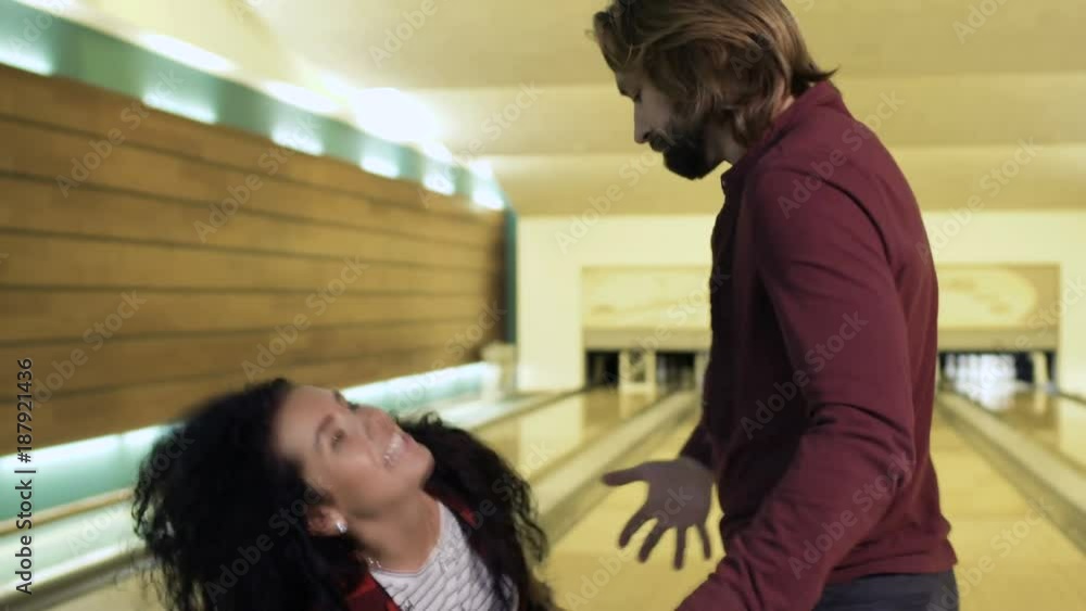 Man gives a heavy bowling ball to woman Man gives a heavy bowling ball to woman