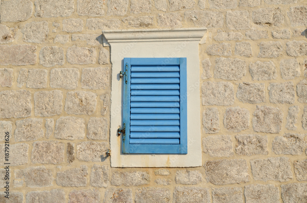 Window with blue wooden jalousie on a coastal house facade