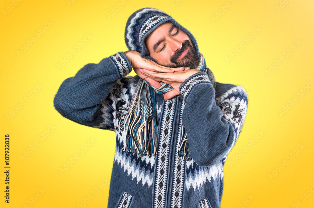 Man with winter clothes making sleep gesture on colorful background Man with winter clothes making sleep gesture on colorful background