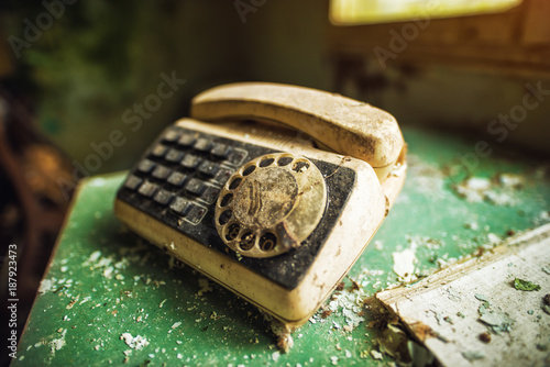Tablou pe pânză Close up focus view of ruined old forgotten damaged telephone on the desk in the abandoned deserted house