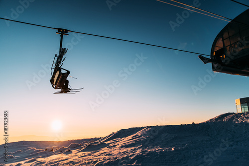 Snowboarder ride on the top of snowy hill in ski resort during calm winter sunset. Scenery of athlete - wallpaper with space for your montage