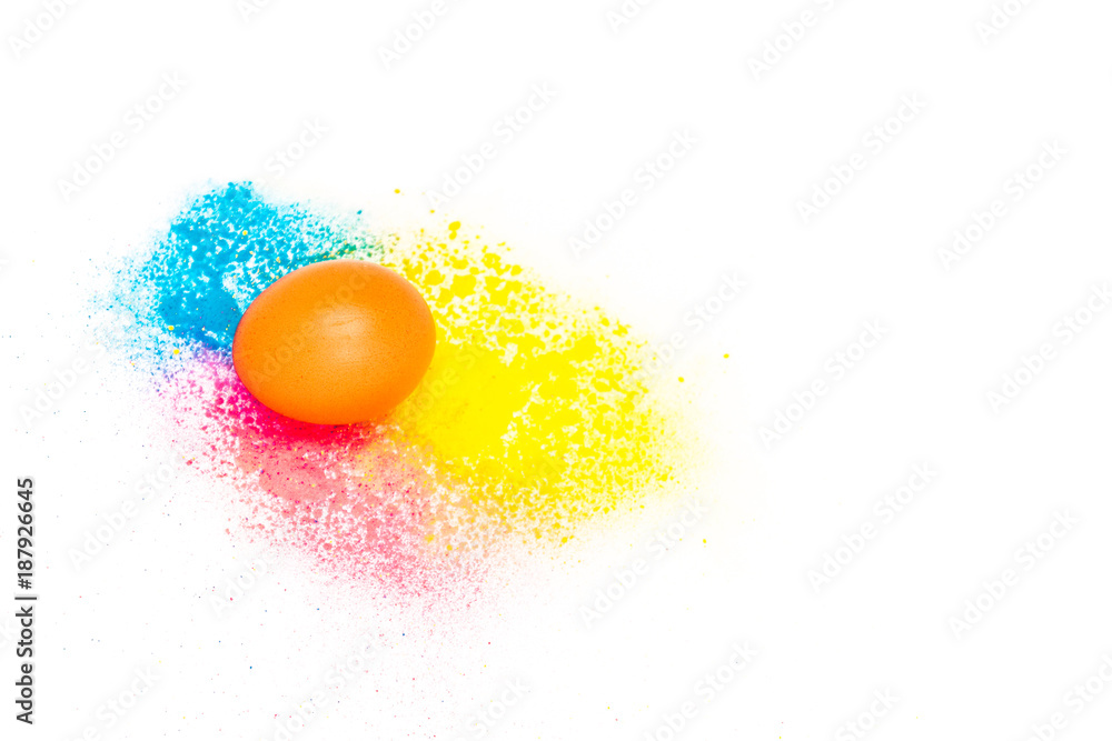 one chicken egg on a background of bright blue and yellow colours on a white background. colored powder. easter concept. one chicken egg on a background of bright blue and yellow colours on a white background. colored powder. easter concept.