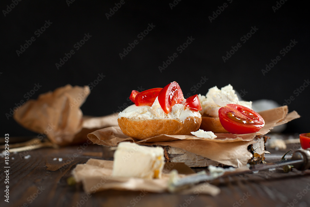 Toast with feta cheese on baking paper, cherry tomatoes and butter on a dark wooden table Toast with feta cheese on baking paper, cherry tomatoes and butter on a dark wooden table