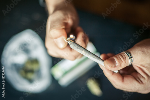 Close up of addict lighting up marijuana joint with lighter photo
