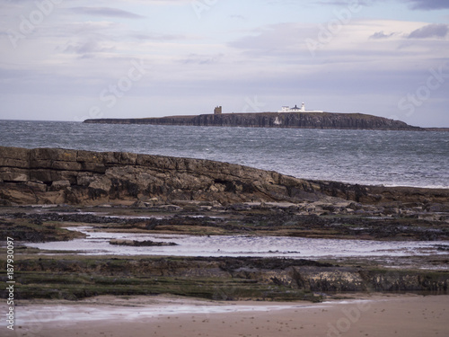 Rocky Ledges on Bamburgh Beach with Island and Lighthouse in Distance