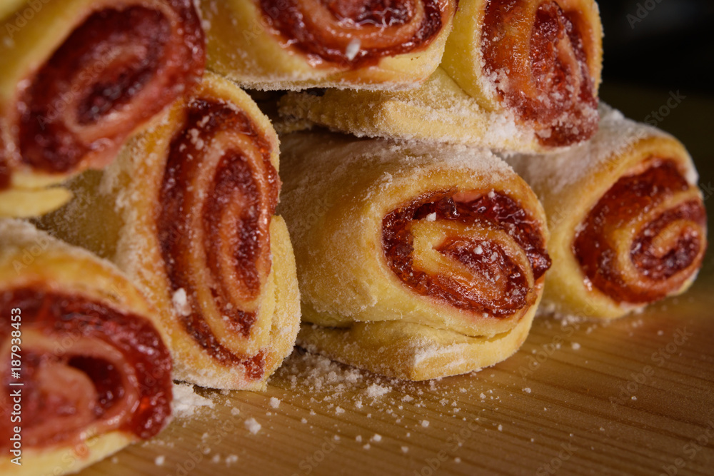 Delicious sweet rolls with red jam stacked on wood desk