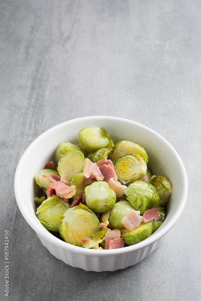 Brussel sprouts and bacon in a white dish on a stone background. Brussel sprouts and bacon in a white dish on a stone background.