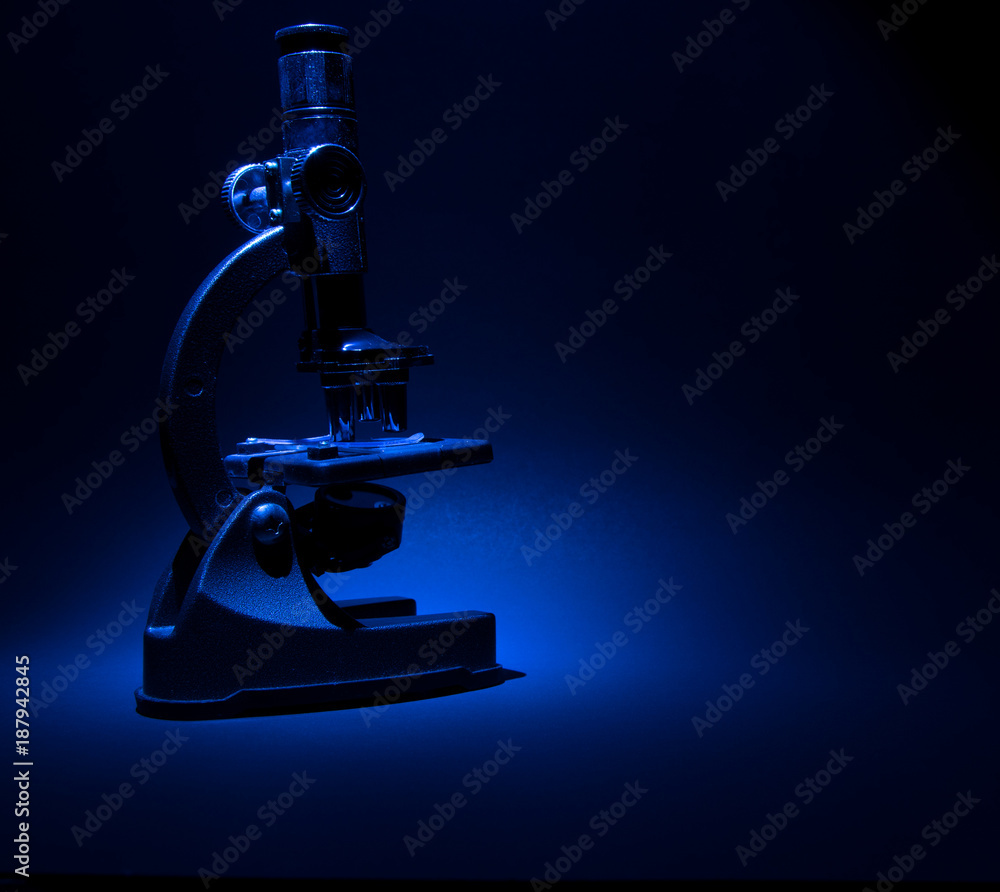 Microscope isolated against blue and black background with blank copy space Microscope isolated against blue and black background with blank copy space