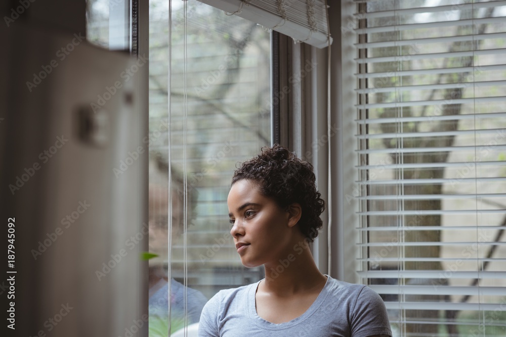 Thoughtful woman looking through window Thoughtful woman looking through window