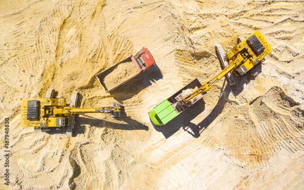Aerial vieAerial view of a excavators and trucks in the mine or construction site. Heavy industry and machinery.w of a excavator and truck in the mine. Industrial background on mining theme.