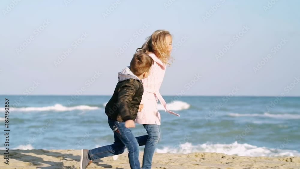 Little brother and sister in warm clothes having fun while running together on beach
Little brother and sister in warm clothes having fun while running together on beach