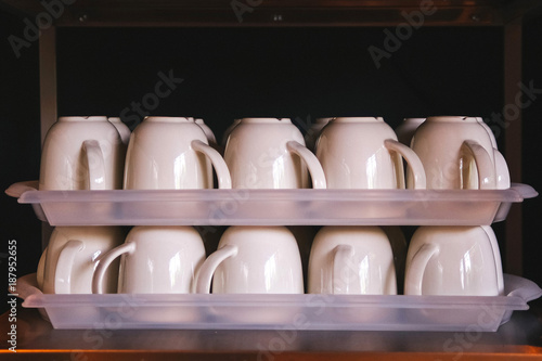 Pure ceramic mugs on a tray. Stack of Coffee cups in restaurant.