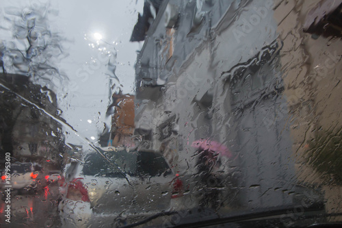 Fototapeta Naklejka Na Ścianę i Meble -  Drops Of Rain On car windshield, Glass Background, Evening. Street Bokeh Lights Out Of Focus