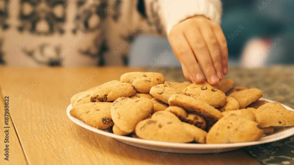 Close up view of Pretty smiling little girl drinking cacao and eating cookies while looking at the camera indoors Close up view of Pretty smiling little girl drinking cacao and eating cookies while looking at the camera indoors