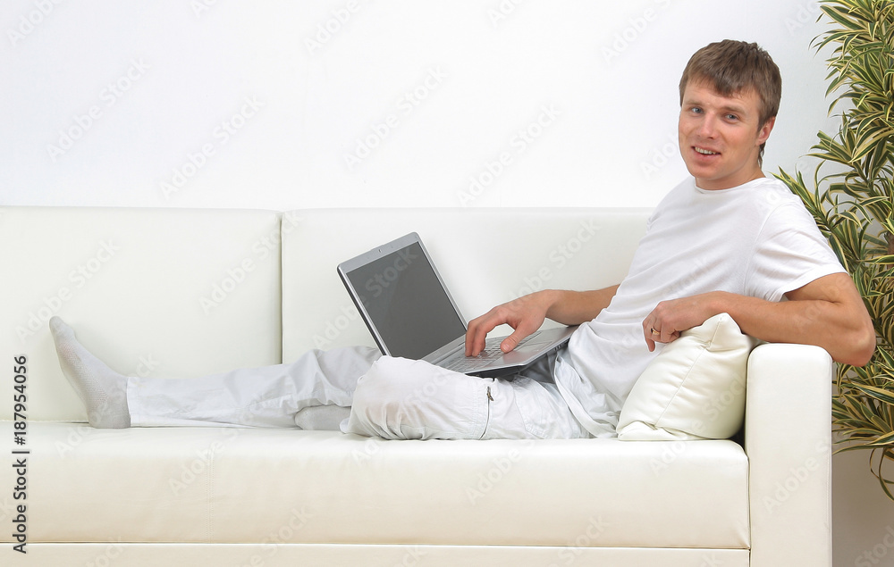Very focused young man using laptop while sitting comfortably. Very focused young man using laptop while sitting comfortably.