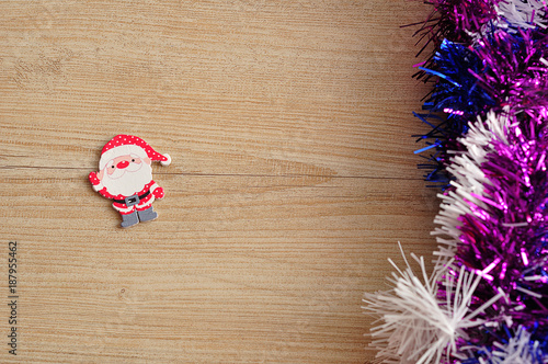 A Santa Clause figurine with purple  blue and white tinsel