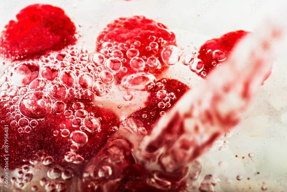 Many bubbles in water with raspberries.