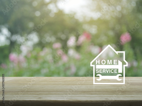 Hammer and wrench with house icon on wooden table over blur pink flower and tree  Business home service concept