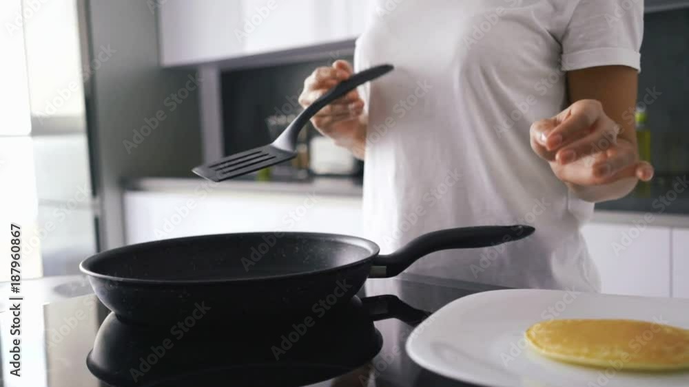 Cropped view of asian woman standing by the stove on kitchen and cooking pancakes Cropped view of asian woman standing by the stove on kitchen and cooking pancakes