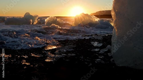 Small icebergs on the shore of a black sand beach in Iceland at sunset. photo