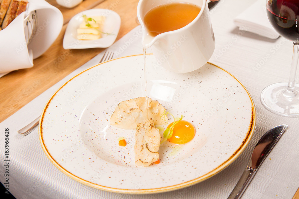 Broth with dumplings and an egg yolk being poured from a jug Broth with dumplings and an egg yolk being poured from a jug