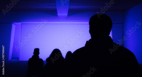 Silhouettes of audience sitting in empty lit theater