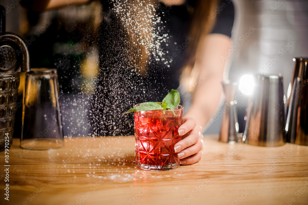barmaid finishes cocktail preparation by adding a bitter of powdered sugar - obrazy, fototapety, plakaty 