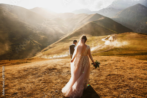 Stylish young wedding couple has fun posing in beautiful Georgian mountains photo