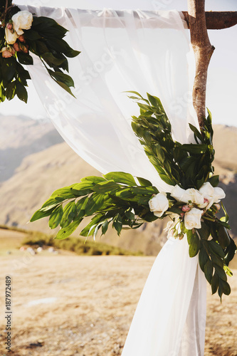 Wedding altar made of wooden blocks, greenery, roses and white cloth stands on the top of the mountain somewhere in Georgia photo