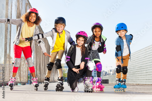 Happy kids rollerblading outdoors at sunny day