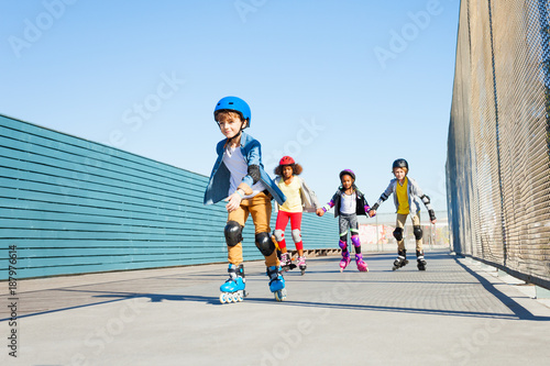 Boy playing roller skates with friends outdoors