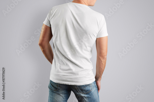 Mockup white T-shirt with a back view on a muscular man with blue jeans