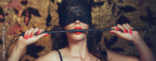 Sexy woman in blindfold bite whip with red lips banner photo