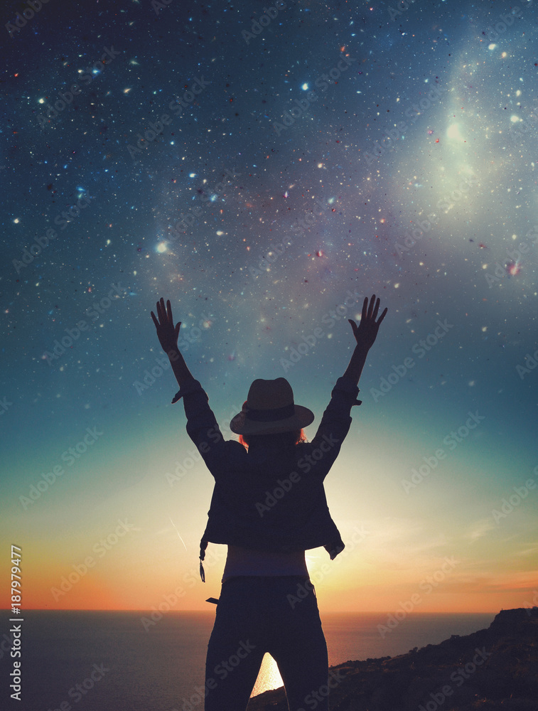Carefree womans silhouette hands up to the stars on cliff Carefree womans silhouette hands up to the stars on cliff