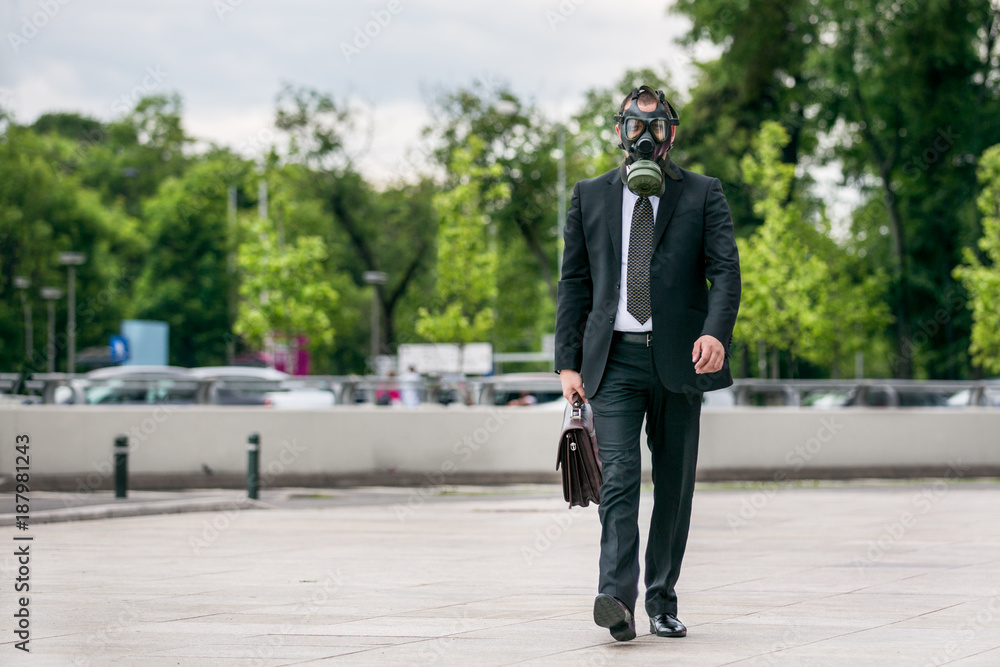 Businessman walking outdoor with briefcase wearing a gas mask on face. Businessman walking outdoor with briefcase wearing a gas mask on face.