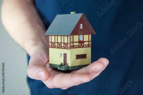 Man holding in hands little toy home