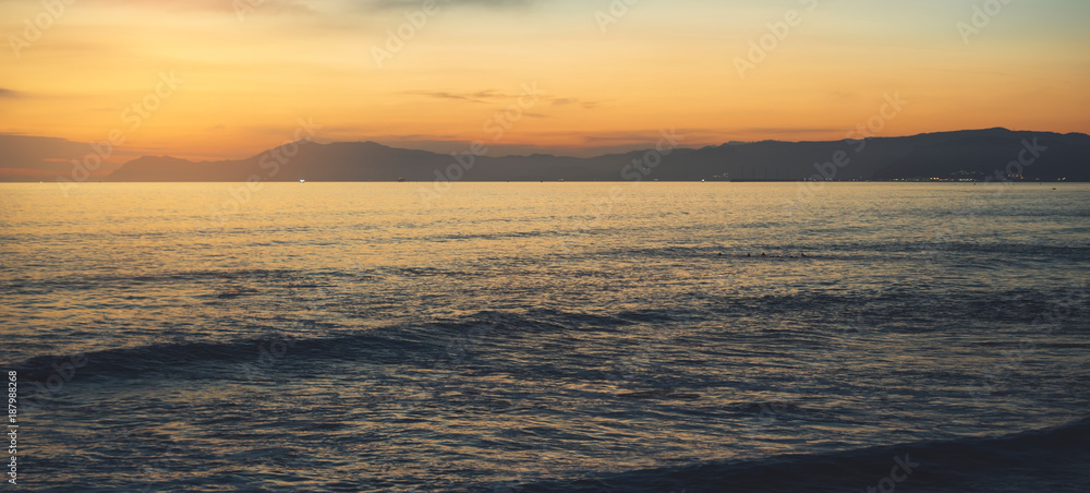 Obraz premium Clouds blue sky and gold sunlight sunset on horizon ocean, background seascape dramatic atmosphere rays sunrise. Relax view waves sea with ship, mockup nature evening concept, copy space for text.