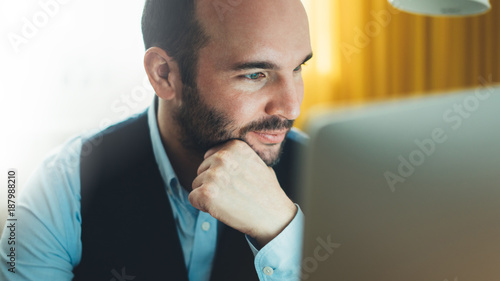 Bearded young businessman working on modern office at night. Consultant man thinking looking in monitor computer. Manager typing on keyboard in coworking workplace, startup project concept in studio photo
