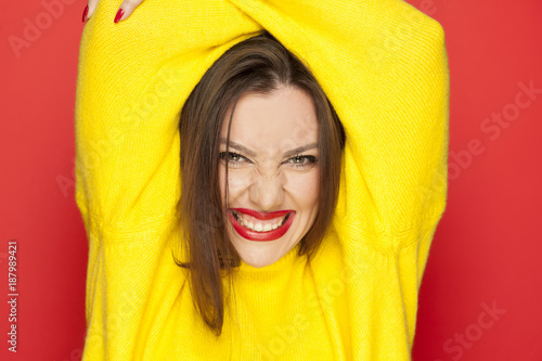 beautiful sexy woman in a yellow blouse showung her teeth on a red background photo