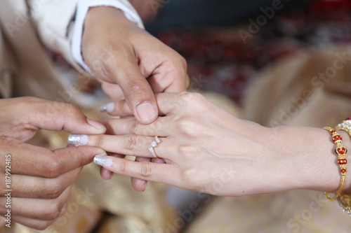 Thai groom wearing wedding ring for his bride © namning