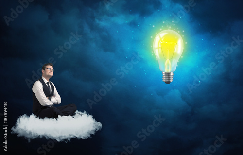 Man sitting on cloud looking at a lightbulb