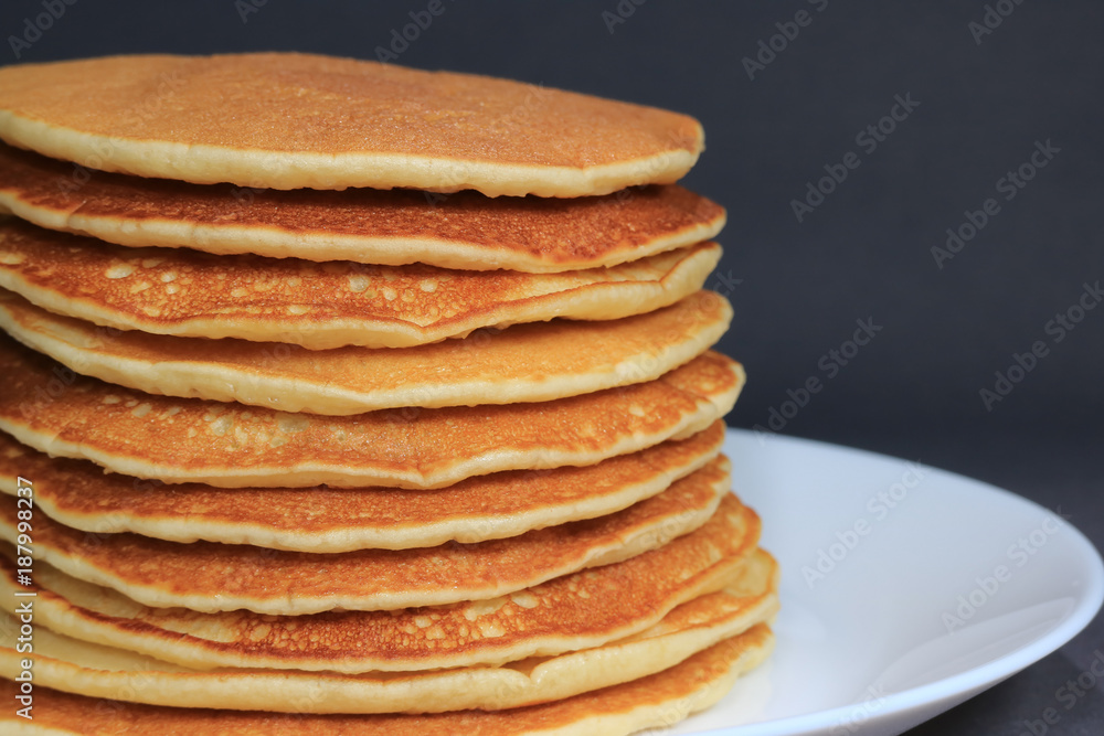 Front view of Stack of homemade plain pancakes served on white plate on black background with selective focus Front view of Stack of homemade plain pancakes served on white plate on black background with selective focus