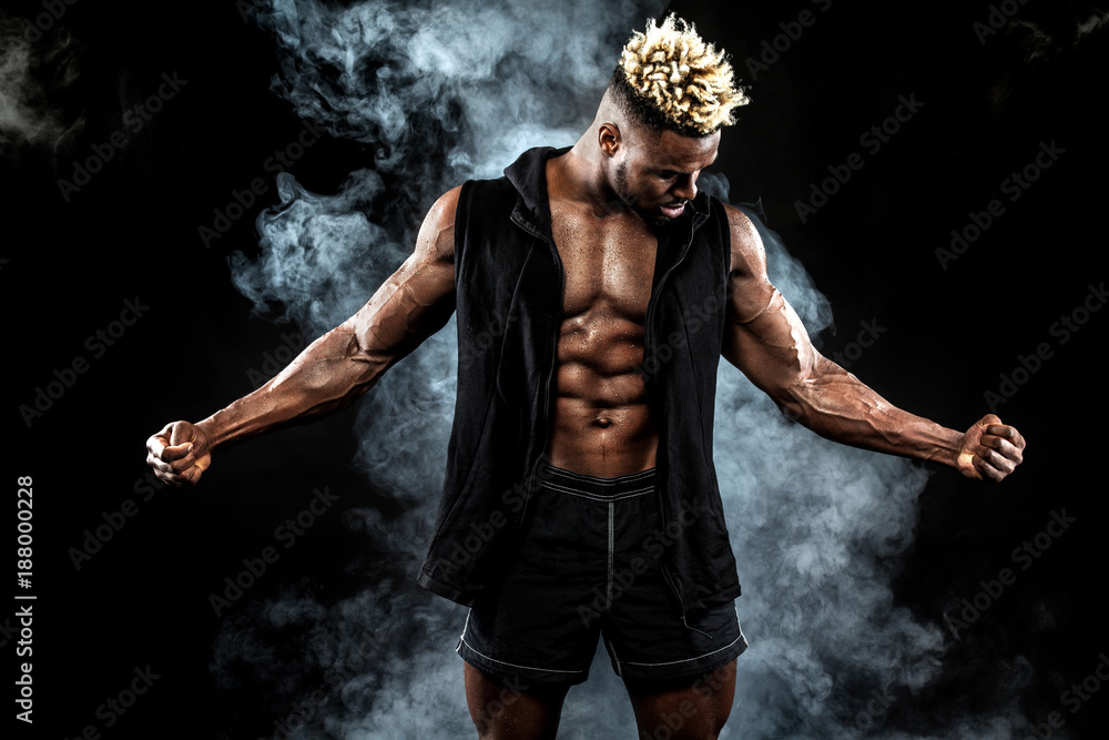 Sports wallpaper on dark background. Power athletic guy bodybuilder. Fire and energy