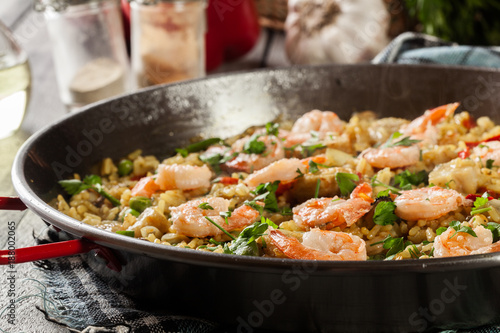 Traditional seafood paella with shrimp, fish and chicken seved in paellera