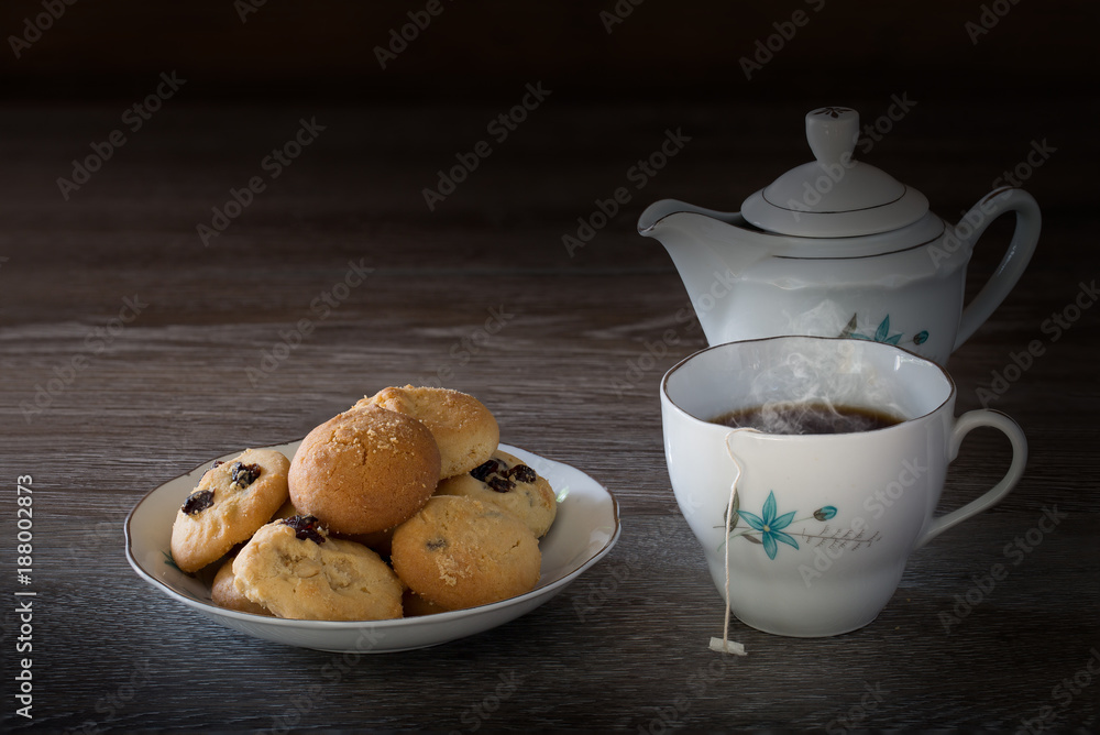 Cookies and English tea set on wooden background in dim light Cookies and English tea set on wooden background in dim light