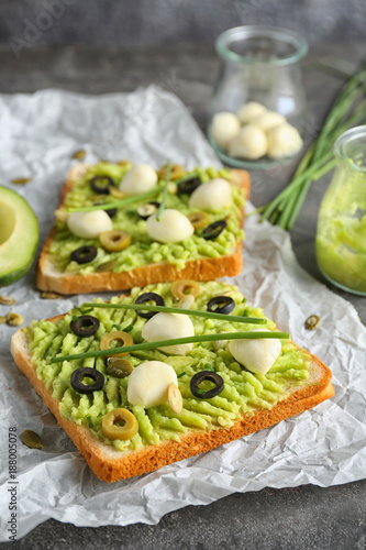 Tasty toasts with avocado paste, cheese and olives on table