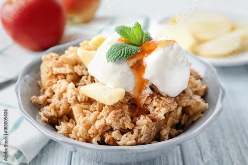 Bowl with apple crisp and ice cream on table, closeup